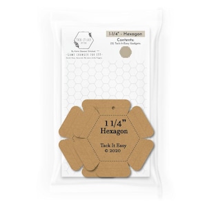 May include: A clear plastic package containing two brown cardboard 1-1/4 inch hexagon templates for quilting. The packaging features the text Tack-It-Easy, 1-1/4 inch Hexagon, and Contents: (2) Tack-It-Easy Gadgets, with a white hexagon grid background.