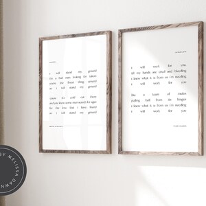 May include: Two framed art prints with black text on a white background. The prints have a wooden frame. The text includes song lyrics. The prints are displayed on a white wall.