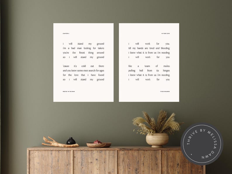 May include: Two framed art prints with minimalist typography on a neutral background. The prints feature song lyrics in a simple, elegant font. The artwork is displayed on a wooden cabinet with decorative items, creating a warm, inviting aesthetic.