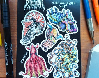 May include: A black sticker sheet with detailed illustrations of marine life, including an octopus, squid, and nautilus. The sheet has the text "PATREON JUNE 2025 STICKER SHEET" and the artist's name. A black marker, pencils, and an eraser are also visible.