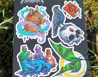 May include: A sticker sheet with a black background featuring a variety of colourful illustrations. The sheet includes a cat with a swirling nebula around it, a raven perched on a skull, a frog with potions, a bat with a crescent moon, and a book with an eye on the cover. The text "PATREON OCTOBER 2024 STICKER SHEET" is at the top of the sheet.
