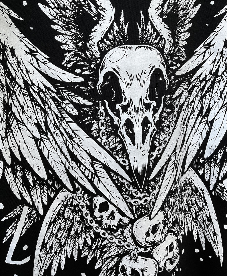 Peut inclure: Design graphique noir et blanc repr&eacute;sentant un cr&acirc;ne avec des ailes et des cha&icirc;nes. Le cr&acirc;ne a un bec d'oiseau et est entour&eacute; de plus petits cr&acirc;nes.