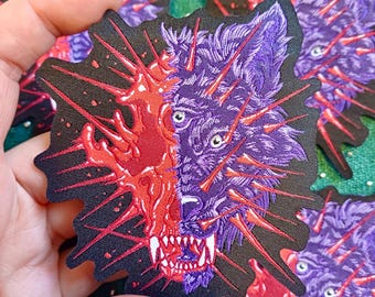 May include: A patch with a split design of a wolf's face. One side is purple, the other is red with a burst effect. The wolf has sharp teeth and is surrounded by red spikes. The patch is on a black background.