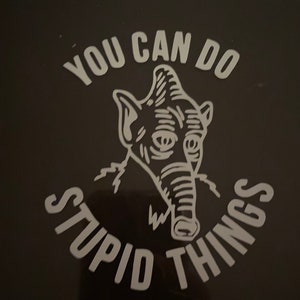 Könnte beinhalten: Schwarzes Quadrat mit weißem Text und einer Strichzeichnung einer elefantenartigen Kreatur. Der Text lautet "YOU CAN DO STUPID THINGS" in einer kreisförmigen Anordnung um den Kopf der Kreatur.