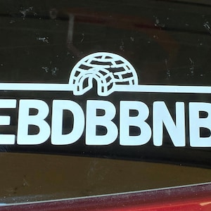 May include: White sticker on a black surface with a stylised igloo design and the text "EBD BBNB".