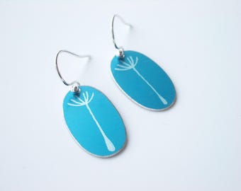 May include: A pair of turquoise blue oval earrings with a white dandelion design. The earrings have silver hooks.