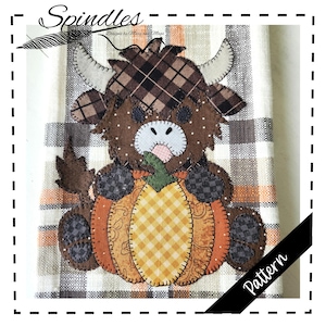 Puede incluir: Un patrón de tela decorativo con una vaca de las Tierras Altas marrón sosteniendo una calabaza. La vaca tiene detalles de cuadros escoceses y está sobre un fondo a cuadros. La palabra "Spindles" está en la parte superior y "Pattern" en una pancarta negra.