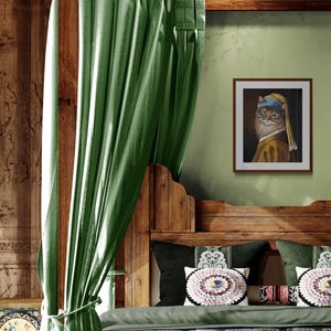 May include: A framed print of a cat in the style of Johannes Vermeer's "Girl with a Pearl Earring" hangs on a green wall. The cat wears a blue headscarf and a yellow and brown outfit. The bed has green pillows and a wooden headboard.