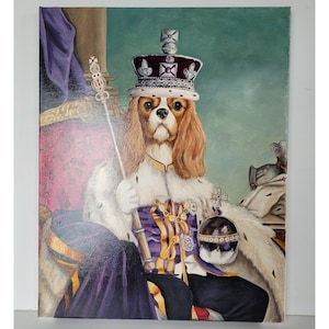 May include: A Cavalier King Charles Spaniel dog wearing a purple and gold royal robe and a crown with jewels. The dog is sitting on a throne with a purple and gold fabric. The background is a green wall.