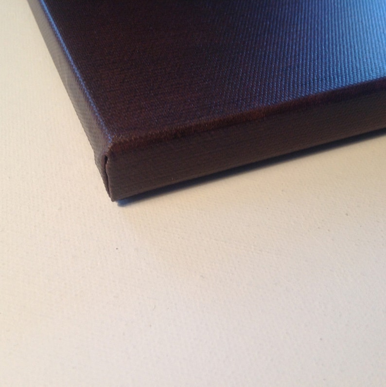 May include: Close-up of a dark brown canvas print. The canvas is stretched over a wooden frame, with the edges neatly folded and secured. The canvas has a textured surface, and the color is a deep, rich brown.