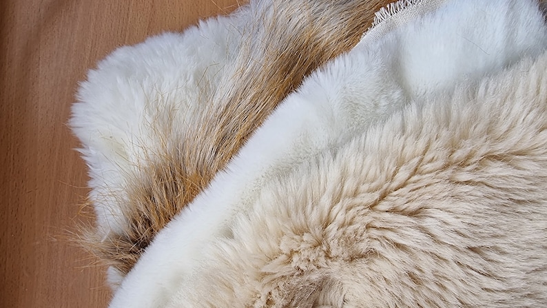 May include: Two pieces of faux fur fabric. One is a light brown color and the other is a white color.