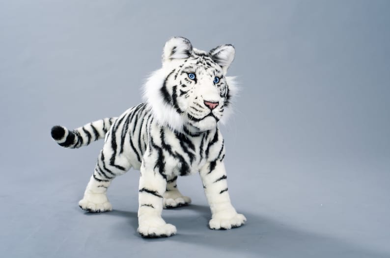May include: A white stuffed tiger with black stripes. The tiger has blue eyes and a fluffy white mane.