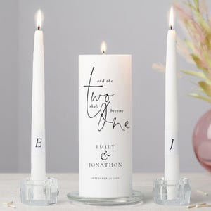 May include: A wedding unity candle set featuring a large pillar candle and two taper candles. The pillar candle has the text "and the two shall become one" with the names Emily & Jonathon and the wedding date. The taper candles have the letters "E" and "J".