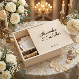 Puede incluir: Una caja de recuerdos de madera de color claro con los nombres "Alexander & Isabella" grabados en la tapa. La caja está abierta, revelando compartimentos con notas y una botella pequeña. La escena está decorada con flores blancas, velas y un mantel decorativo.