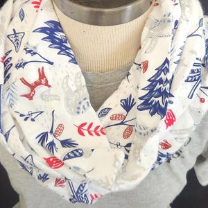 May include: White infinity scarf with a blue, red, and gray woodland animal print. The print features foxes, owls, and trees.