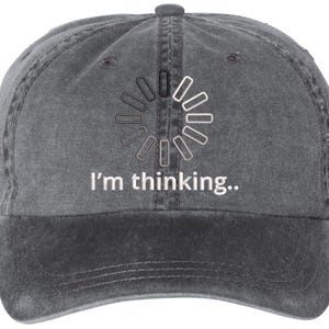 May include: A black denim baseball cap with a white loading icon and the text "I'm thinking..." embroidered on the front.