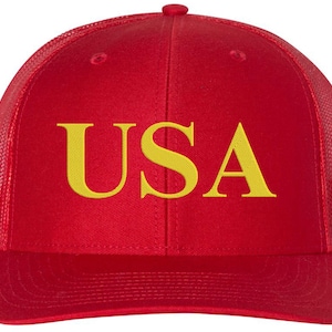 Pode incluir: Bon&eacute; de caminhoneiro vermelho e preto com um "USA" bordado em amarelo na frente.