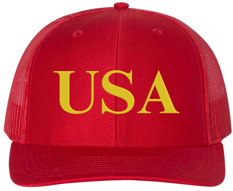 Pode incluir: Bon&eacute; de caminhoneiro vermelho e preto com um "USA" bordado em amarelo na frente.