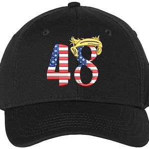 May include: Black baseball cap featuring the embroidered number "48". The "4" is designed with the American flag, and the "8" has a gold-colored design. The cap has a curved peak and a button on top.