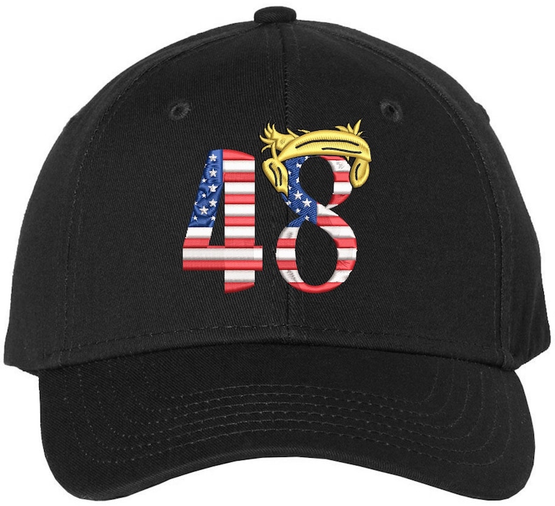 May include: Black baseball cap featuring the embroidered number "48". The "4" is designed with the American flag, and the "8" has a gold-colored design. The cap has a curved peak and a button on top.
