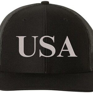 Pode incluir: Bon&eacute; de caminhoneiro preto e cinza com um "USA" bordado em branco na frente.