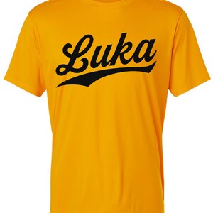 May include: A yellow t-shirt with a black "Luka" graphic in a vintage baseball style font.