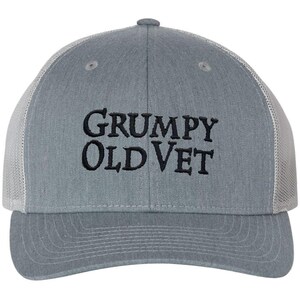May include: A gray and white trucker hat with black embroidered text that reads "GRUMPY OLD VET".