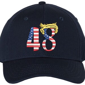 May include: A navy blue baseball cap featuring the embroidered number "48" on the front. The numbers are designed with the American flag pattern. Above the number "8" is a gold-colored design.