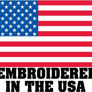 Pode incluir: Texto bordado "Embroidered in the USA" em um fundo branco com uma bandeira americana vermelha, branca e azul.