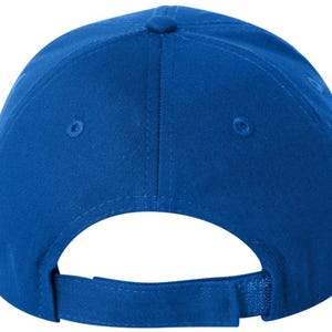 May include: A royal blue baseball cap, seen from the rear. It has a curved peak, a fabric strap with a metal clasp for adjustment, and a small button on the crown. The material looks like a sturdy cotton or similar fabric.