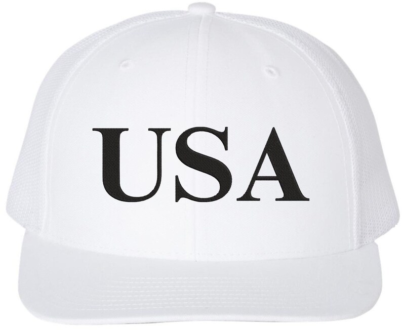 Pode incluir: Bon&eacute; de caminhoneiro branco com parte de tr&aacute;s em malha preta e a palavra "USA" em letras pretas na frente.