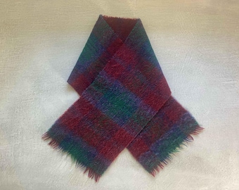 May include: A red, green and blue plaid scarf with a fringed edge.