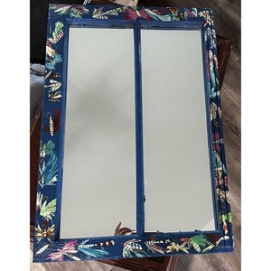 May include: A blue mirror with a double frame decorated with colorful fishing lures. The mirror is divided into two sections.