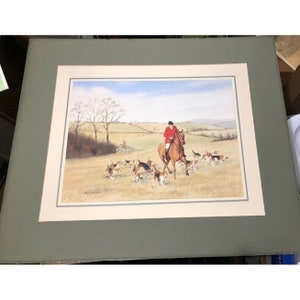May include: A watercolor painting of a hunter on horseback leading a pack of hounds through a field. The hunter is wearing a red coat and a black hat. The hounds are running in a line, with their tails wagging.