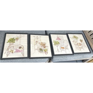 May include: Set of four framed prints featuring black and white illustrations of wicker furniture and plants. The prints are in black frames and have a vintage aesthetic.