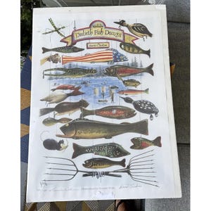 May include: A white poster with a colorful illustration of various fish decoys. The decoys are hanging from a string and are arranged in a vertical line. The poster is titled "Duluth Fish Decoys" and is signed by David E. Perkins and Jerome Wells.