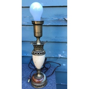May include: A vintage table lamp with a white and gold base and a clear glass shade. The base is decorated with a floral design and the shade is frosted.