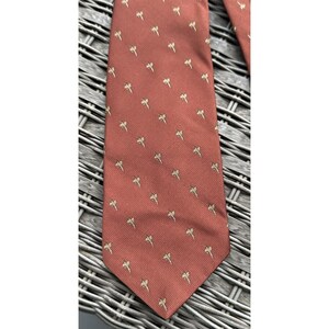 May include: A red silk tie with a pattern of small, gold palm trees.