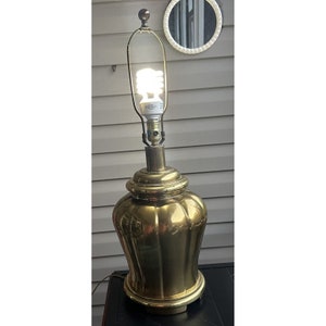 May include: A gold table lamp with a fluted base and a clear glass shade. The lamp is turned on and the light bulb is visible.