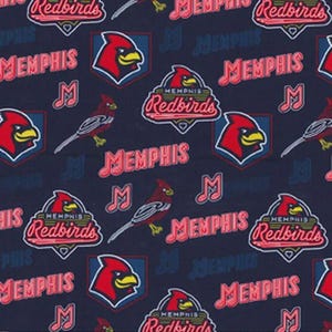 May include: A dark blue fabric featuring a repeating pattern of the Memphis Redbirds baseball team logo, including the red cardinal bird head, the team name in red text, and musical note symbols, with a ruler showing inches at the bottom.