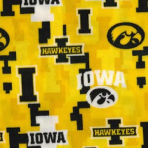 May include: Yellow fabric with a repeating pattern of black and white "IOWA" and "HAWKEYES" text, a black and white stylized hawk logo, and black and white geometric shapes.