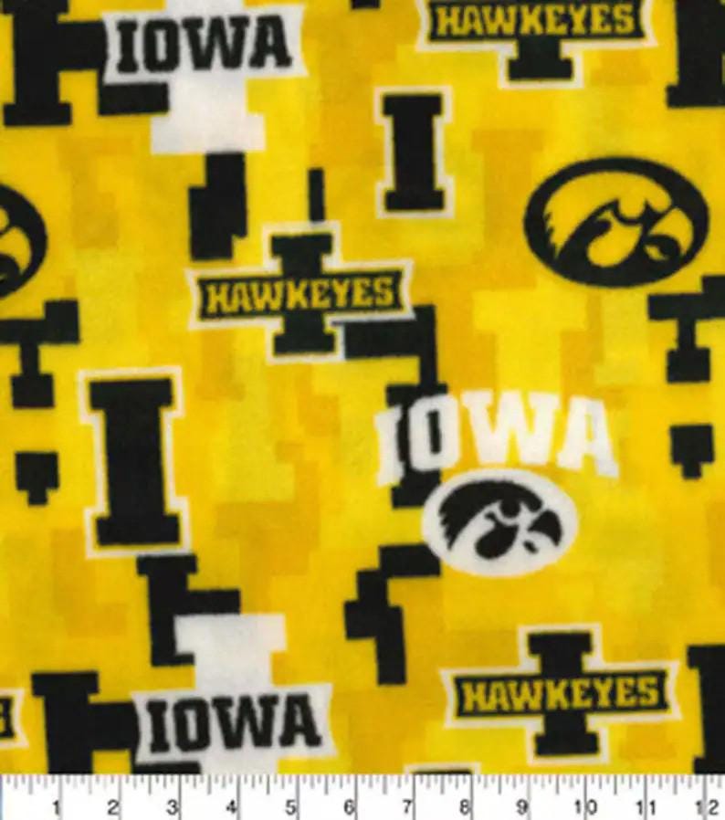 May include: Yellow fabric with a repeating pattern of black and white "IOWA" and "HAWKEYES" text, a black and white stylized hawk logo, and black and white geometric shapes.
