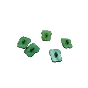Puede incluir: Cinco botones peque&ntilde;os de color verde claro con forma de cuatro l&oacute;bulos similar a un tr&eacute;bol. Cada bot&oacute;n presenta un ojal central en la superficie superior para su fijaci&oacute;n. Los botones tienen un acabado mate y liso, dispuestos dispersos.