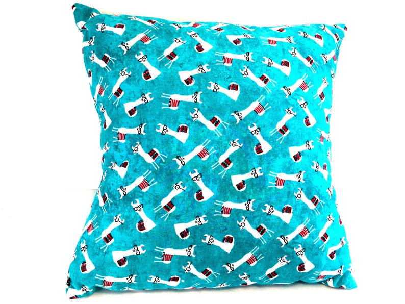 May include: A square throw cushion featuring a vibrant turquoise background with a repeating pattern of white llamas. Each llama is depicted wearing black-rimmed glasses and a small red and white striped blanket draped across its back.