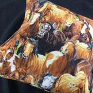 May include: A square throw pillow featuring a detailed, colorful print of a herd of horses. The design displays multiple horses in various shades of brown, chestnut, black, and white, captured in a close-up, overlapping composition.