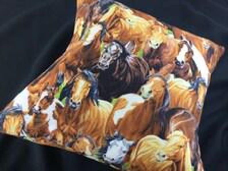 May include: A square throw pillow featuring a detailed, colorful print of a herd of horses. The design displays multiple horses in various shades of brown, chestnut, black, and white, captured in a close-up, overlapping composition.