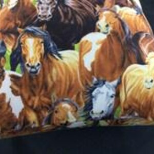 May include: A fabric pillowcase featuring a detailed, colorful print of multiple horses in various shades of brown, chestnut, and white. The horses are depicted in a group, showing different facial expressions and manes against a green background.