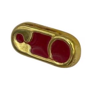 以下が含まれることがあります： 赤いエナメルを施した金色の安全ピンチャーム。チャームはジュエリーやチャームブレスレットに人気のある追加アイテムです。