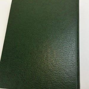 May include: A dark green book cover with a textured, leather-like appearance. The cover is rectangular and appears to be part of a bound book. The edges are smooth and the overall aesthetic is classic and simple.