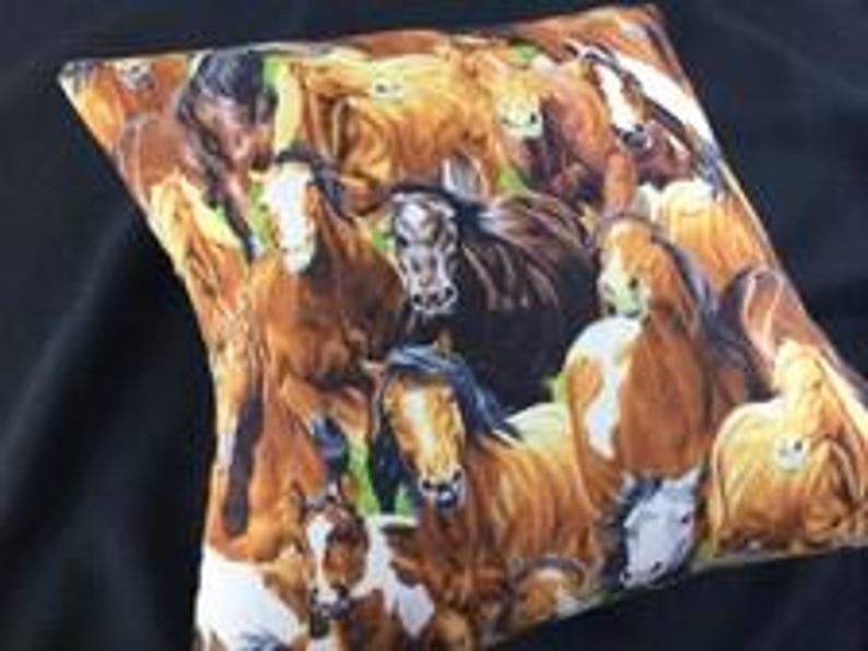May include: A square throw pillow featuring a vibrant, repeating pattern of multiple horses in various shades of brown, chestnut, and white. The horses are depicted in close proximity, showcasing detailed manes, facial markings, and expressive eyes.
